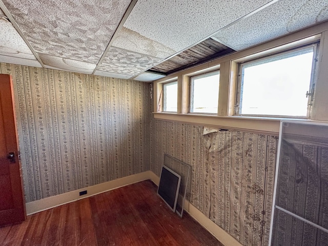 basement with a drop ceiling and wood-type flooring