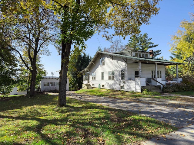 view of side of home with covered porch and a lawn