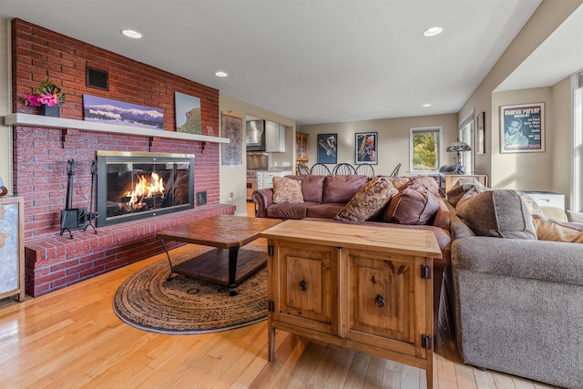 living room with light hardwood / wood-style floors and a brick fireplace