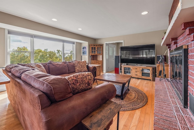 living room with a brick fireplace and light wood-type flooring