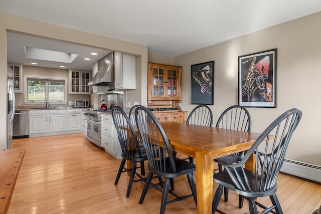 dining space with light hardwood / wood-style floors, a skylight, and sink