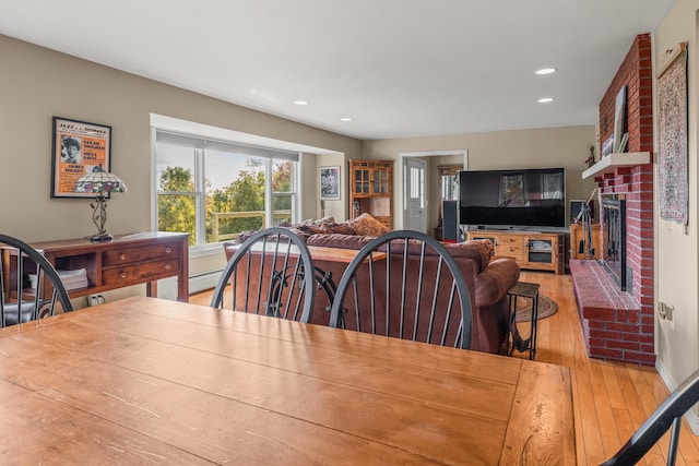 dining space featuring light hardwood / wood-style floors and a brick fireplace