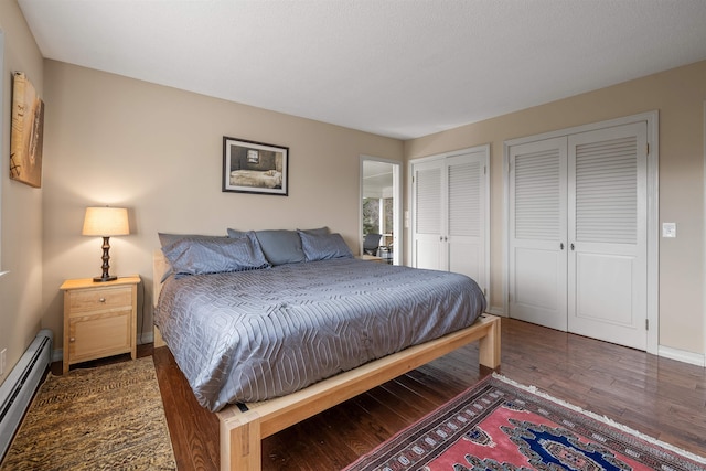 bedroom featuring dark hardwood / wood-style floors, multiple closets, and a baseboard radiator