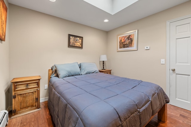 bedroom with a baseboard radiator and hardwood / wood-style floors