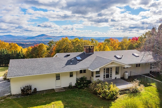 rear view of property with a mountain view and a yard