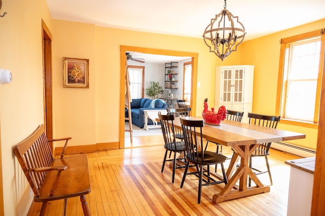 dining space featuring a baseboard radiator, light wood-type flooring, and a healthy amount of sunlight