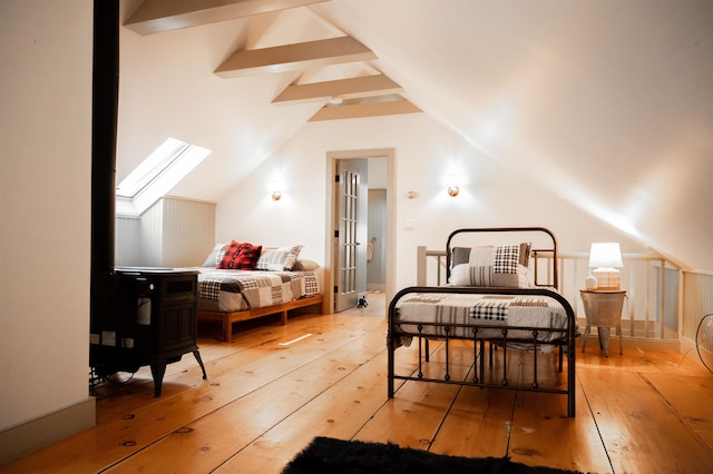 bedroom featuring lofted ceiling with skylight and hardwood / wood-style floors