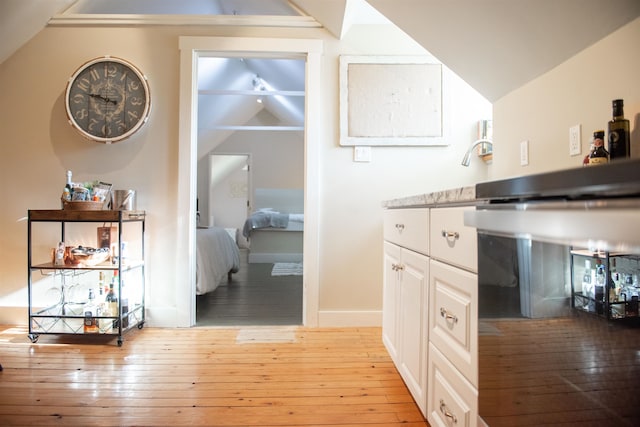 kitchen with white cabinetry, light hardwood / wood-style flooring, and lofted ceiling