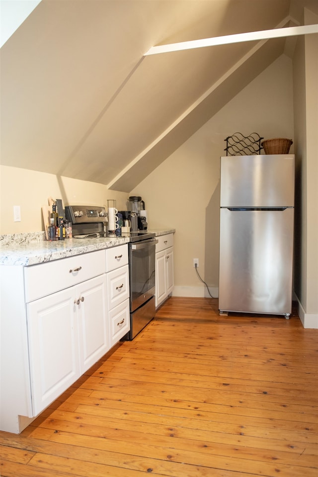 kitchen with stainless steel appliances, vaulted ceiling, light wood-type flooring, and white cabinets