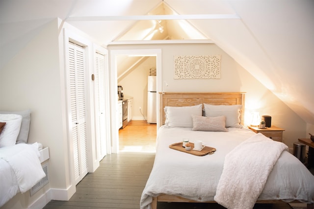 bedroom featuring lofted ceiling, hardwood / wood-style flooring, and white refrigerator