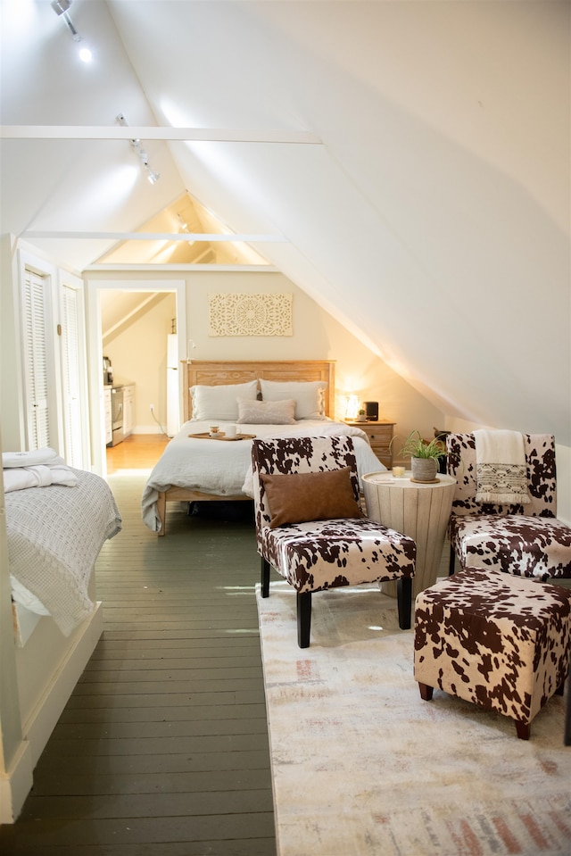 bedroom featuring hardwood / wood-style floors, vaulted ceiling, and rail lighting