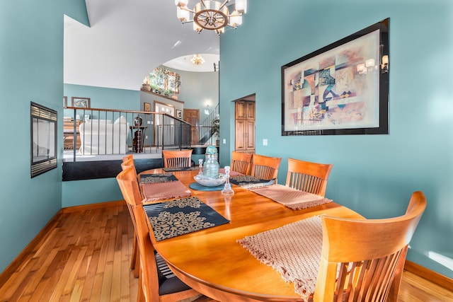 dining room with light hardwood / wood-style floors, a high ceiling, and an inviting chandelier