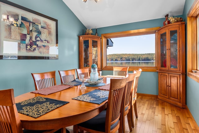 dining area featuring light hardwood / wood-style floors, vaulted ceiling, and a notable chandelier