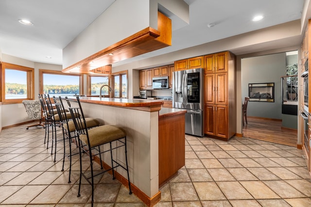 kitchen featuring appliances with stainless steel finishes, a kitchen breakfast bar, sink, a kitchen island, and light tile patterned flooring