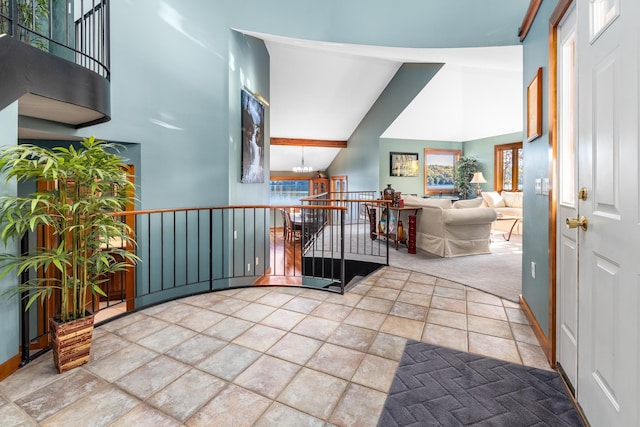 entrance foyer featuring beam ceiling, a healthy amount of sunlight, an inviting chandelier, high vaulted ceiling, and carpet floors