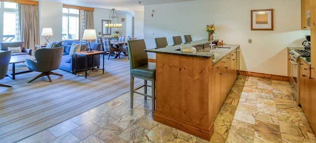 kitchen featuring sink, a kitchen bar, stainless steel gas stove, kitchen peninsula, and a chandelier