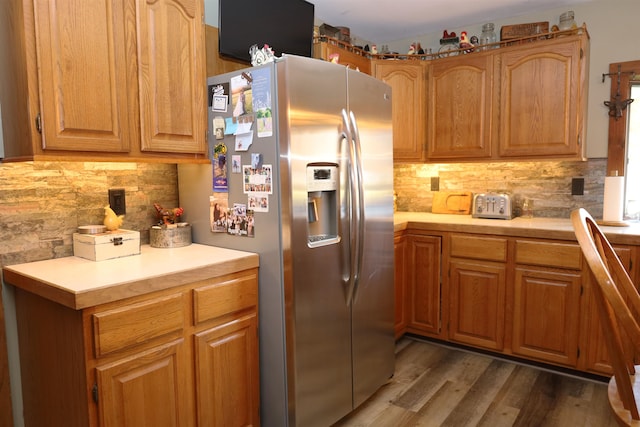 kitchen with dark wood-type flooring, tasteful backsplash, and stainless steel fridge