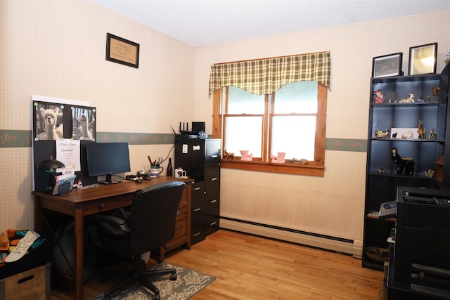 home office with light hardwood / wood-style flooring and a baseboard heating unit