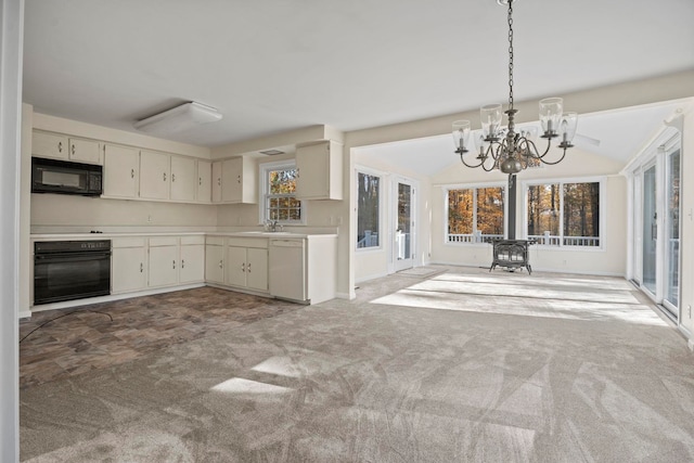 kitchen with black appliances, sink, a wood stove, carpet floors, and vaulted ceiling