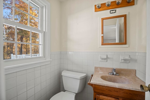 bathroom featuring toilet, vanity, and tile walls