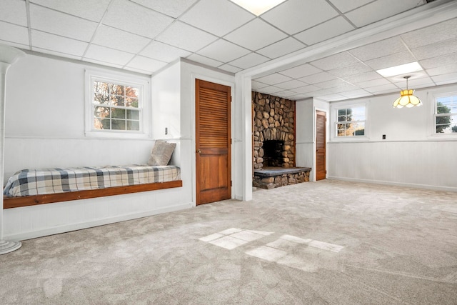 basement featuring a drop ceiling, carpet flooring, and a fireplace