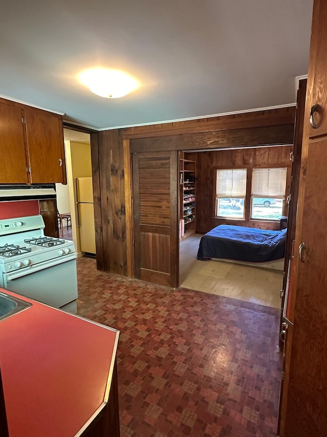 kitchen with wooden walls, wood-type flooring, white appliances, and extractor fan