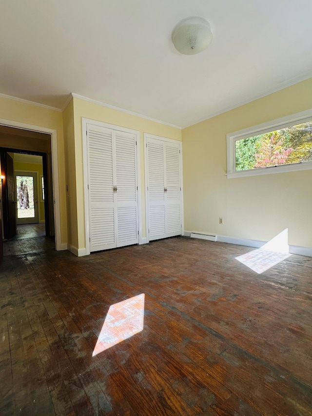 unfurnished bedroom with dark hardwood / wood-style floors, two closets, crown molding, and multiple windows