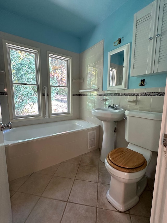 bathroom featuring a washtub, tile patterned floors, toilet, and a healthy amount of sunlight