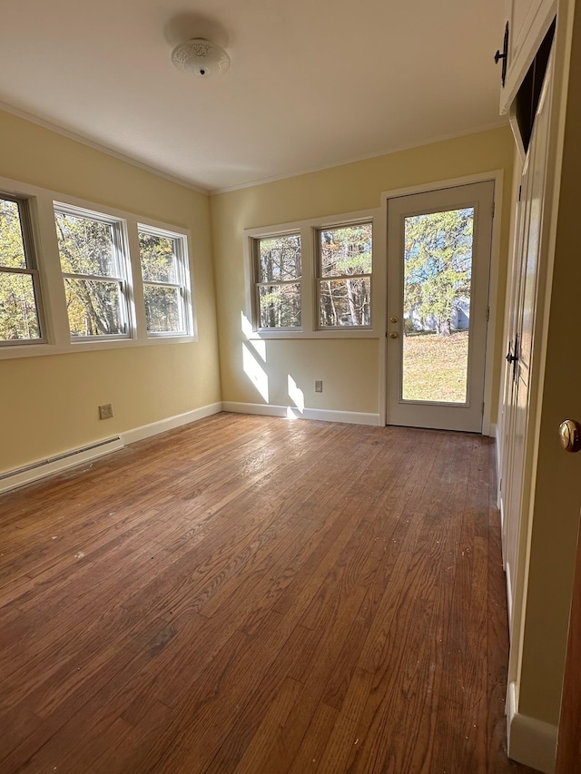 empty room featuring hardwood / wood-style floors, baseboard heating, and plenty of natural light