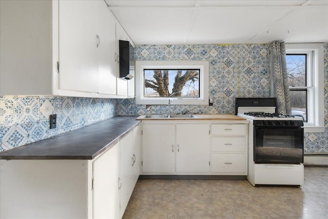 kitchen featuring decorative backsplash, white range with gas stovetop, white cabinetry, and sink