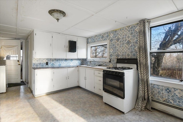 kitchen with white gas range, a baseboard heating unit, sink, and white cabinets