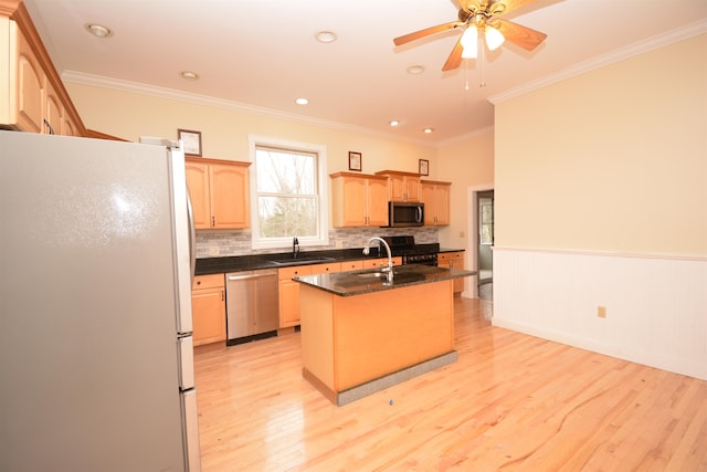 kitchen with appliances with stainless steel finishes, sink, light hardwood / wood-style floors, ornamental molding, and a center island with sink