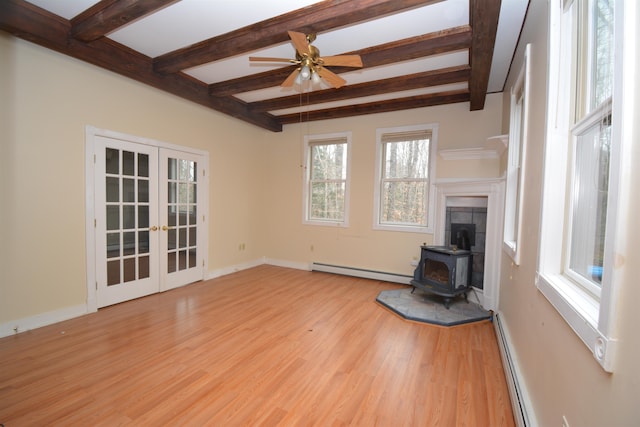 unfurnished living room with light hardwood / wood-style flooring, a wood stove, baseboard heating, and beamed ceiling