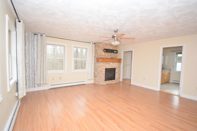 unfurnished living room with a healthy amount of sunlight, baseboard heating, and light wood-type flooring