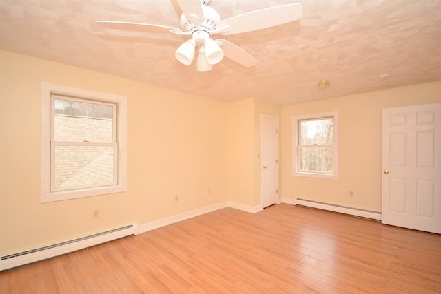 empty room with light hardwood / wood-style flooring, a baseboard heating unit, and ceiling fan