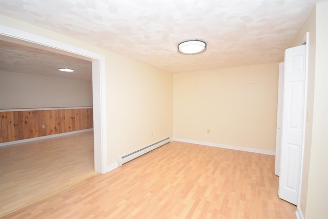 empty room with light hardwood / wood-style floors, a textured ceiling, and a baseboard heating unit