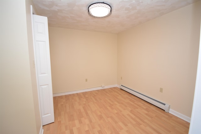 empty room featuring light hardwood / wood-style flooring, a textured ceiling, and a baseboard radiator