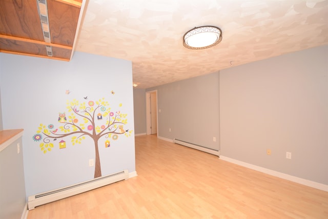 spare room featuring baseboard heating and hardwood / wood-style flooring