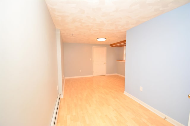 spare room featuring a baseboard radiator and light wood-type flooring