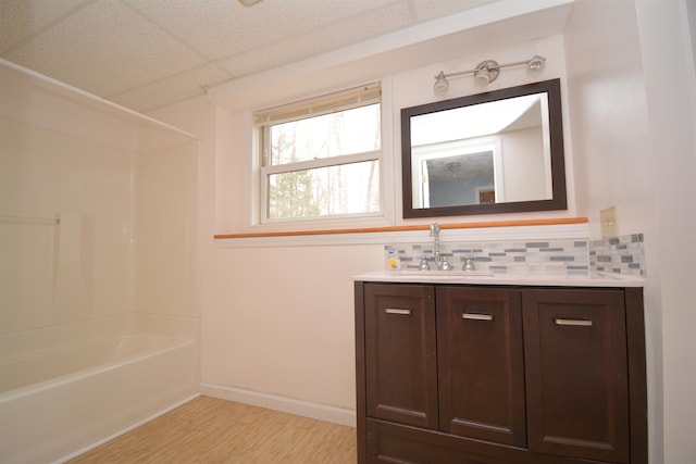 bathroom featuring tasteful backsplash, wood-type flooring, a drop ceiling, shower / tub combination, and vanity