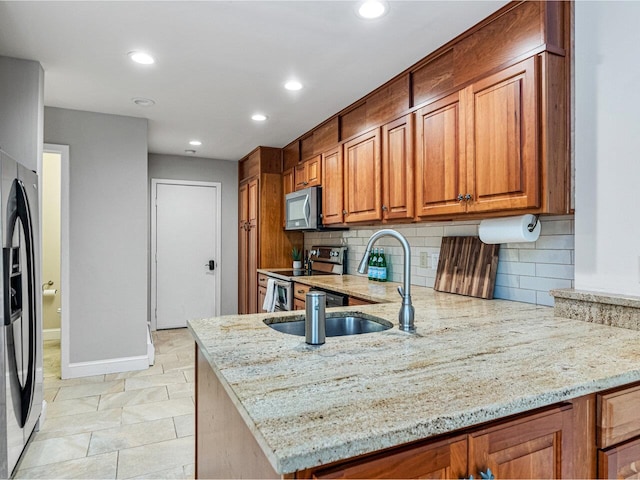 kitchen with backsplash, stainless steel appliances, light stone countertops, and kitchen peninsula