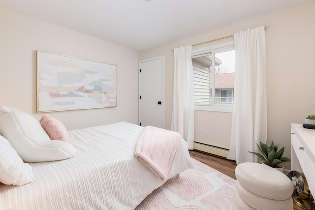 bedroom with baseboard heating and hardwood / wood-style floors