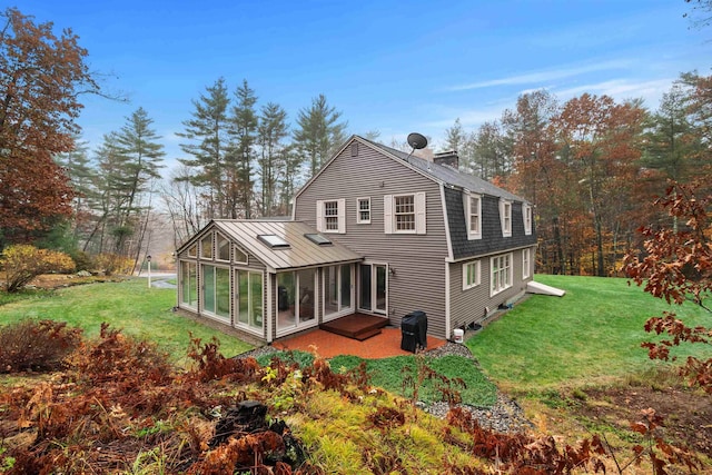 rear view of house featuring a yard and a sunroom