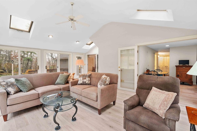 living room with vaulted ceiling with skylight, ceiling fan, and light hardwood / wood-style floors