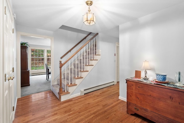 staircase with baseboard heating and wood-type flooring