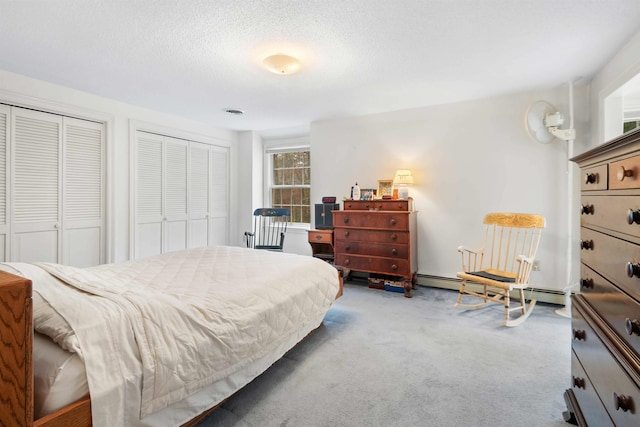 carpeted bedroom with a baseboard heating unit, two closets, and a textured ceiling