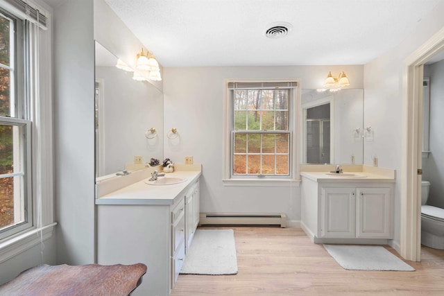 bathroom with toilet, a baseboard heating unit, wood-type flooring, vanity, and walk in shower