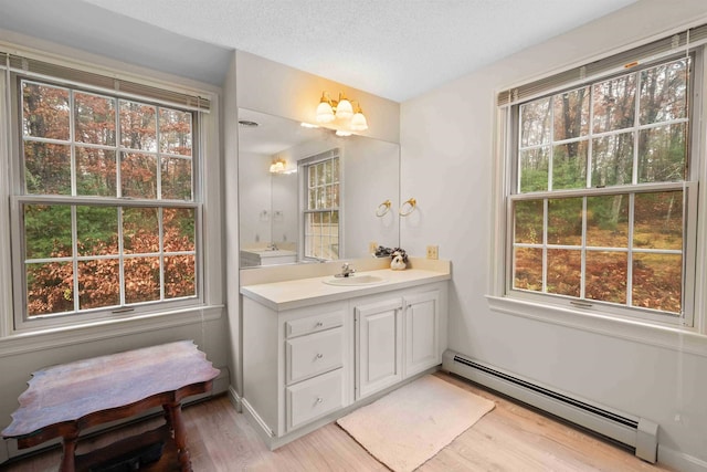 bathroom featuring vanity, a baseboard radiator, a textured ceiling, and hardwood / wood-style flooring