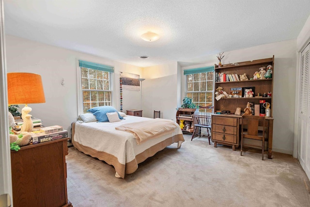 bedroom featuring a textured ceiling, light colored carpet, and a closet