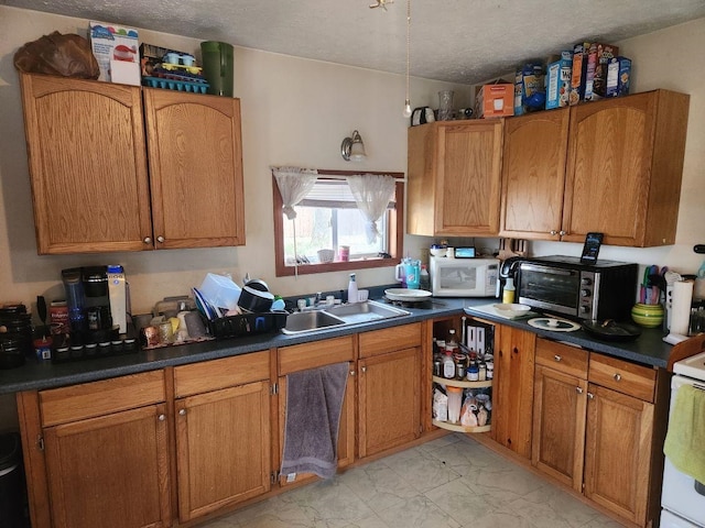 kitchen with a textured ceiling, white appliances, and sink